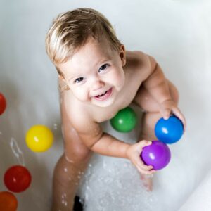 Enfant en train de jouer avec des balles colorées dans une baignoire