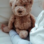 Enfant en train de jouer avec une peluche marron en forme d'ours