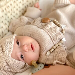 Bébé allongé dans son lit avec une tétine attaché à sa robe