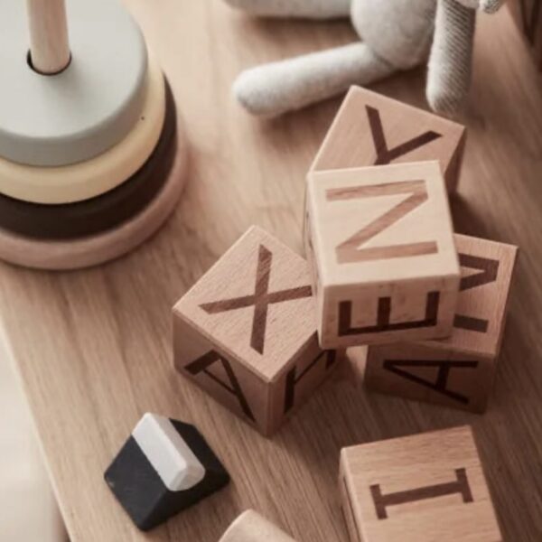 Cubes en bois avec des lettres gravées entourés par d'autres jouets
