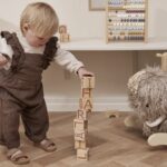 Enfant en train d'empiler des cubes en bois gravés avec des lettres