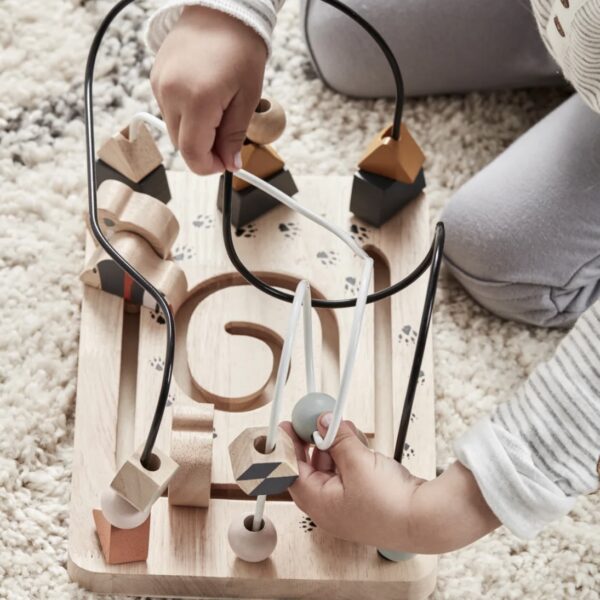 Enfant jouant avec un labyrinthe en bois avec des figurines et des perles