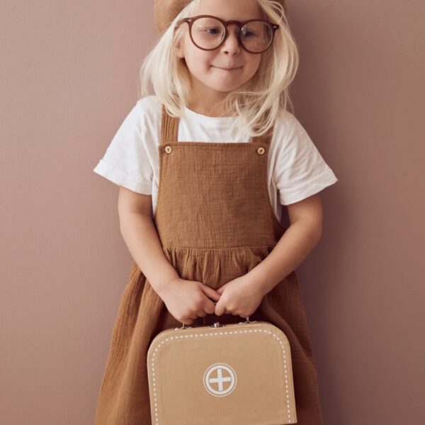 Jeune fille blonde portant une mallette de docteur en bois