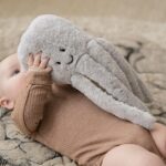 Une peluche en forme de pieuvre dans les bras d'un bébé allongé