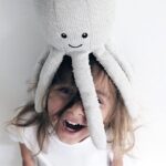 Une peluche en forme de pieuvre posée sur la tête d'une enfant