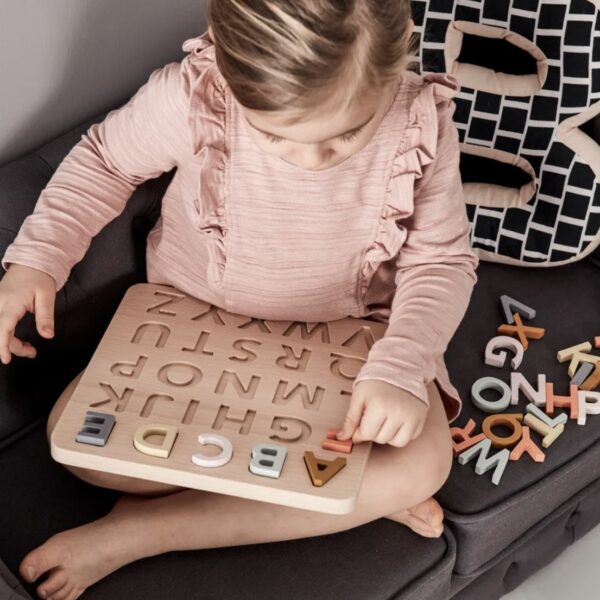 Fille jouant avec un puzzle avec les lettres de l'alphabet colorées en bois