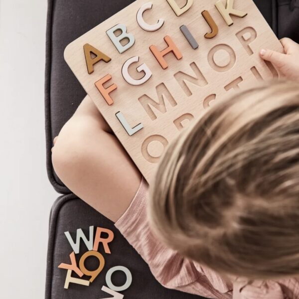Fille jouant avec un puzzle avec les lettres de l'alphabet colorées en bois