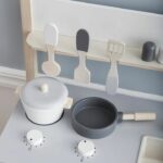 une cuisine jouet en bois blanc avec de la vaisselle et des accessoires pour cuire