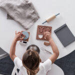 Enfant jouant sur une table avec un jeu d'imitation en bois avec balance, rouleau à pâtisserie, moule et accessoires