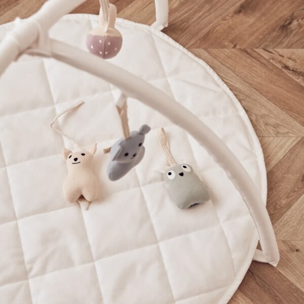 Portique pour les bébés avec des figurines suspendues, posé sur un tapis d'éveil