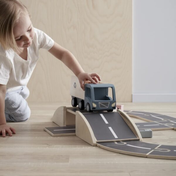 Enfant en train de pousser un camion sur un circuit de jeu en bois