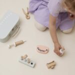 Enfant jouant avec son jeu d'imitation en bois coloré comprenant une mallette et tous les accessoires du dentiste