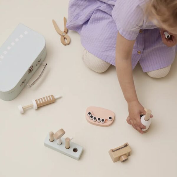 Enfant jouant avec son jeu d'imitation en bois coloré comprenant une mallette et tous les accessoires du dentiste