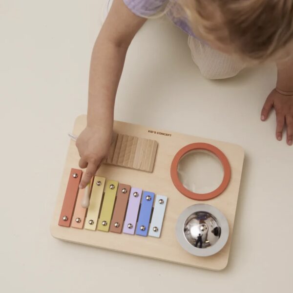 Enfant jouant avec son jouet en bois réunissant plusieurs instruments de musique