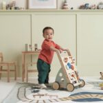 Enfant poussant son trotteur multi-activités en bois coloré dans sa chambre