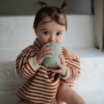 Bébé en train de boire dans un gobelet en silicone avec couvercle à bec