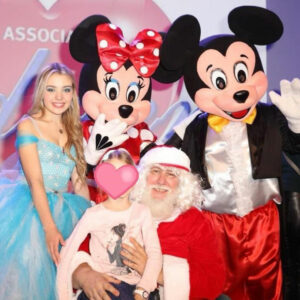 Une petite fille entourée du Père Noël, Mickey, Minnie et la Reine des Neige