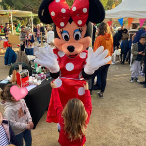 La mascotte Minnie qui se promène dans un marché de Noël avec des enfants